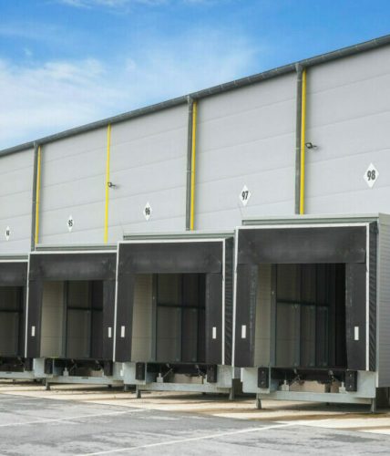 Warehouse loading docks on a sunny day. Open gates of an industrial warehouse. Storehouse doors in a row. Distribution warehouse with open doors.